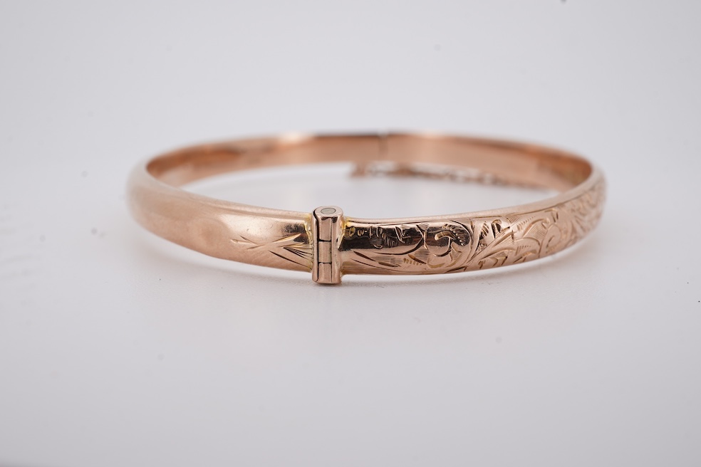 A George V part engraved 9ct gold hollow hinged bangle, Birmingham, 1911, interior diameter 57mm, 5.5 grams. Condition - poor